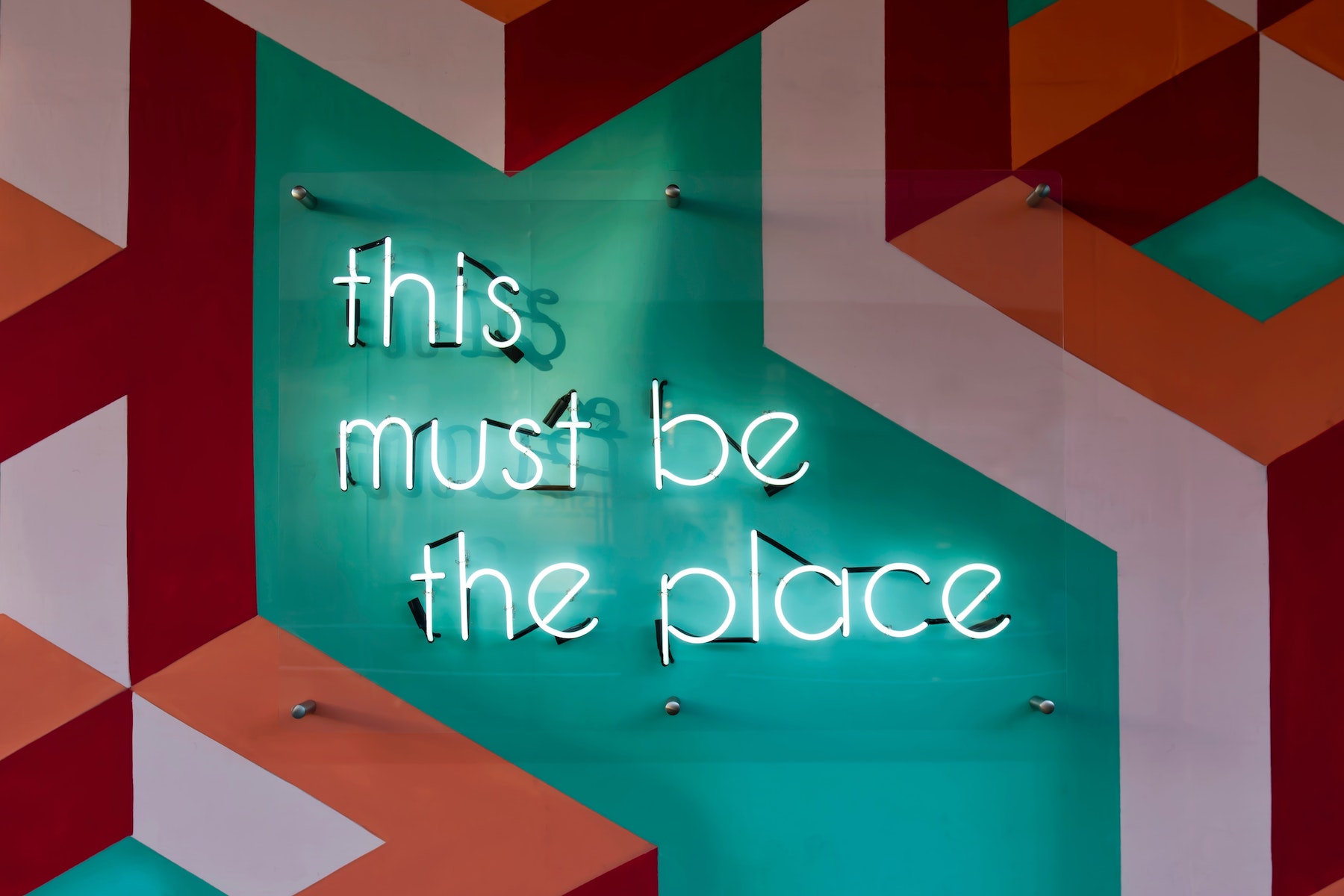 neon sign that reads "this must be the place" on vibrant background