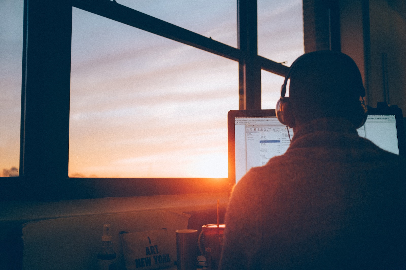 man sits in front of computer with sunset in background
